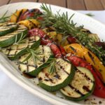 "Colorful assortment of grilled vegetables including zucchini, bell peppers, eggplant, and cherry tomatoes with char marks"