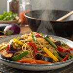 Close-up of stir-fried eggplant, garlic, and vegetables sizzling in a wok or skillet.
