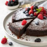 A whole Vegan Almond Flour Cocoa Cake on a serving plate, showcasing its rich chocolate color and moist, dense texture.