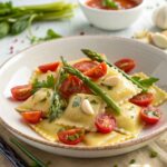 Close-up of fresh ravioli topped with vibrant tomatoes, asparagus, garlic, and herbs, showcasing the dish’s colorful and inviting presentation