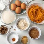 All ingredients for Protein Pumpkin Muffins including pumpkin puree, eggs, yogurt, flour, spices, and protein powder