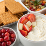 Ingredients for No-Bake Christmas Mini Cheesecakes including cream cheese, graham crackers, and fruits.