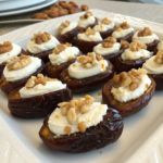 A platter of stuffed dates filled with cream cheese and topped with chopped nuts.