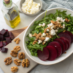 Healthy Roasted Beet Salad ingredients on countertop — beets, greens, goat cheese, walnuts, vinaigrette